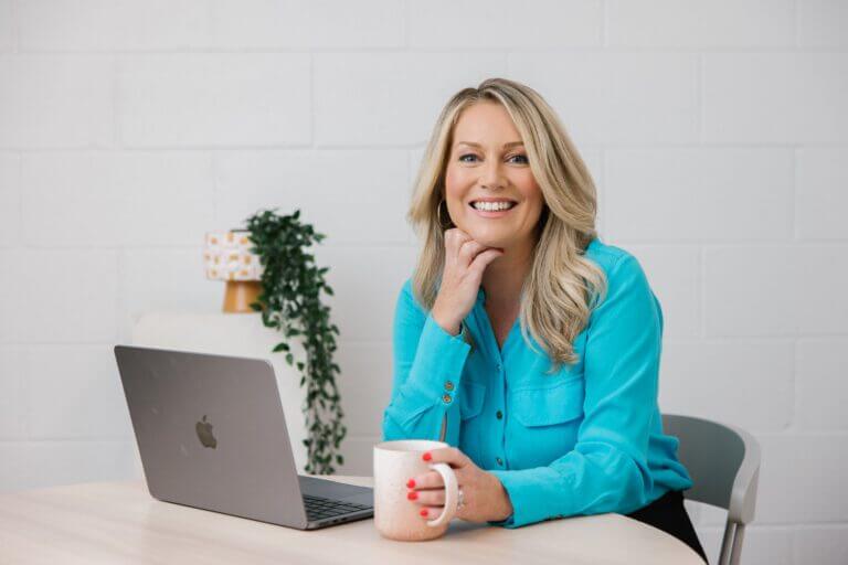 Tammy Barton, Founder and Director of MyBudget, sitting at a desk with a laptop and coffee mug