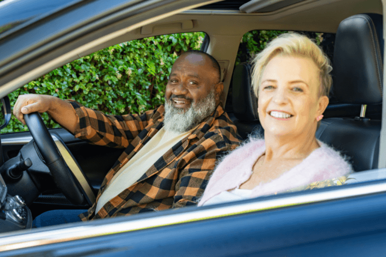 Kim and Bob, MyBudget New Zealand clients, smiling in their car after reducing debt and taking control of their finances.